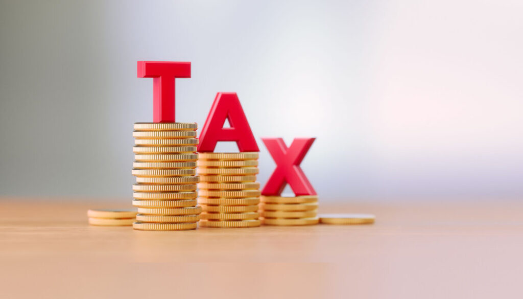 Tax Reduction Concept - Red Letters Sitting On Coin Stacks Write Tax Before Defocused Background